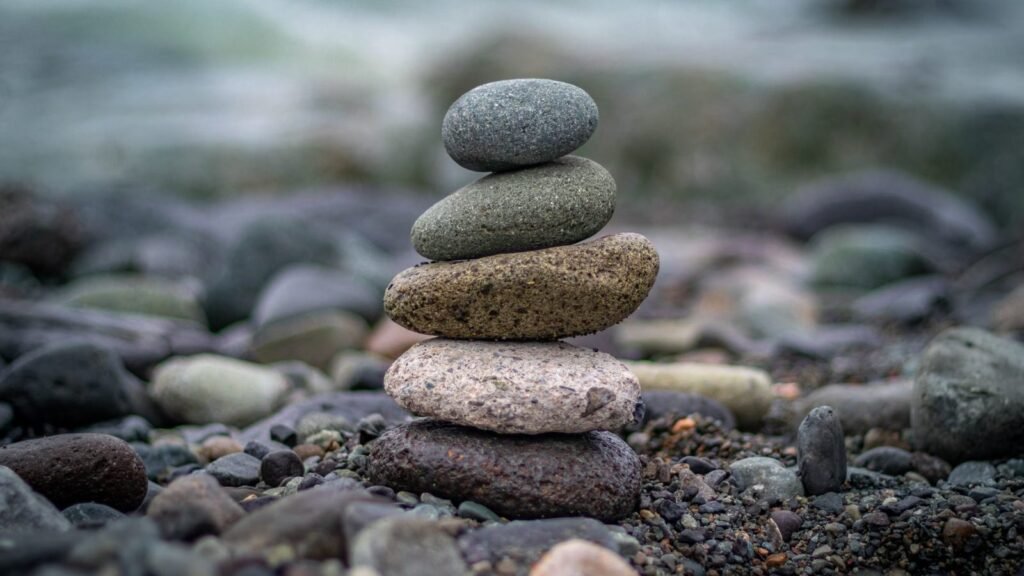 A serene stack of balanced stones with a calm sea backdrop