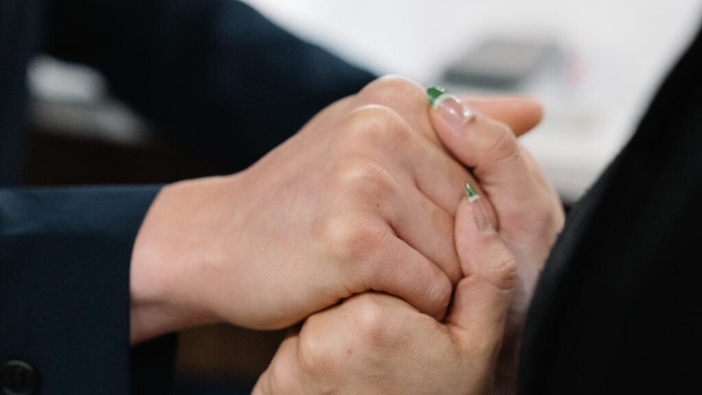 Close-up of two people holding hands in a gesture of comfort and support