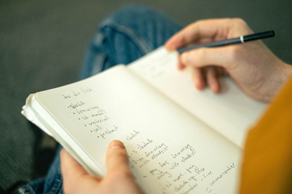 Person writing a to-do list, representing measuring progress toward confidence goals