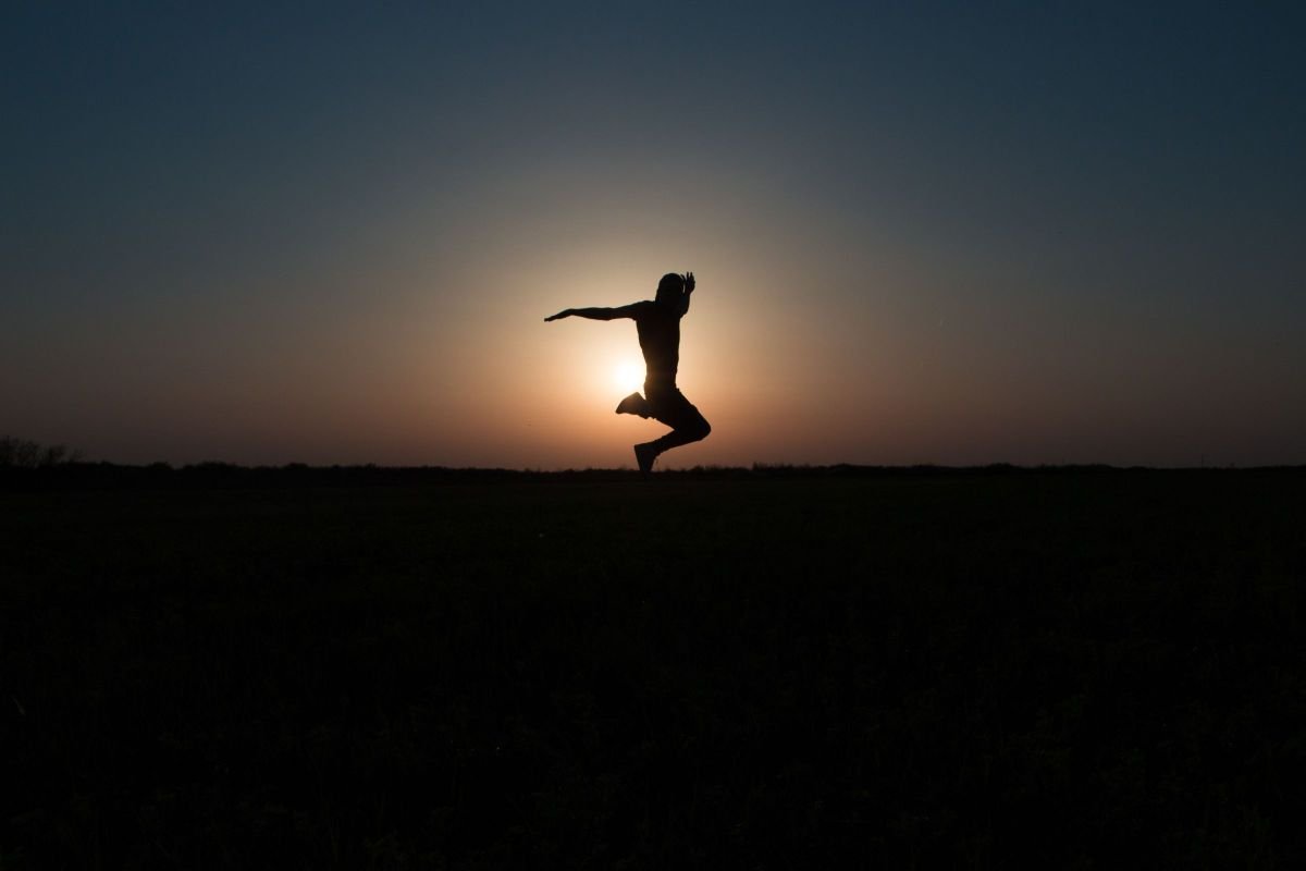 Silhouette leaping joyfully against a sunset sky, symbolising courage and risk-taking