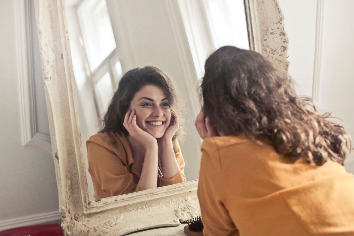 Woman smiling at her reflection, embracing a positive self-image