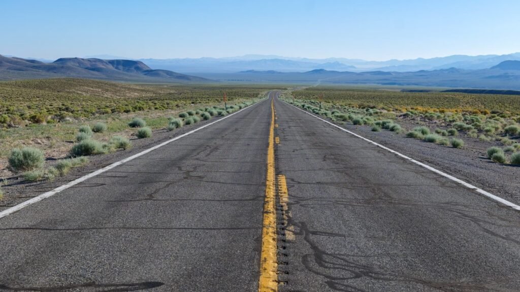 A long empty road stretching through a vast desert landscape