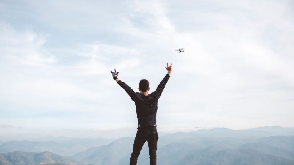 Man with arms raised on a mountain top, celebrating freedom and achievement