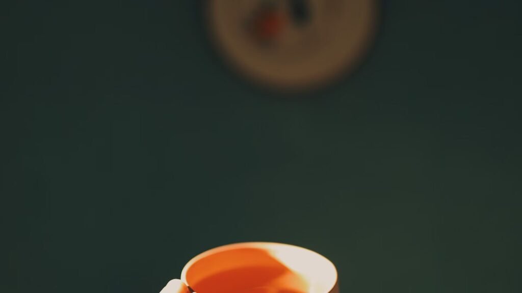 A hand reaching out with a cup of tea in a sunlit room