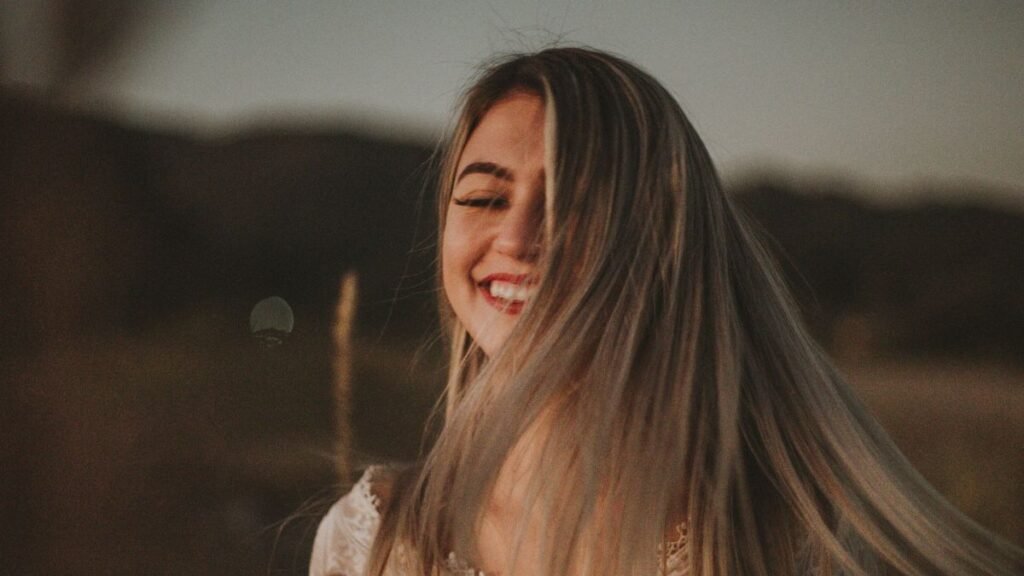 A joyful woman smiling outdoors at sunset
