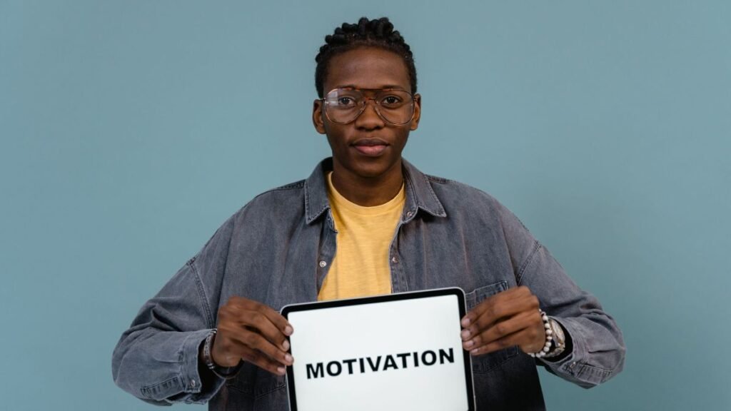 A young man holding a tablet displaying the word Motivation