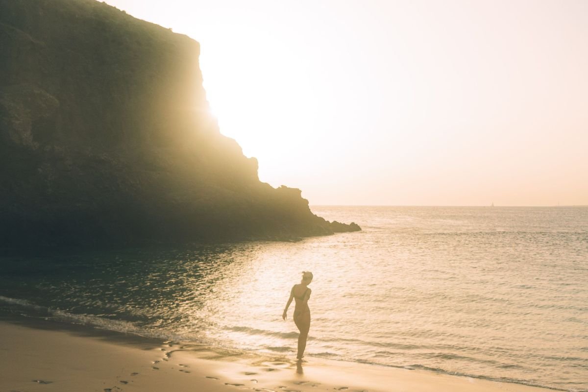 Silhouette of a person walking peacefully along the beach at sunset