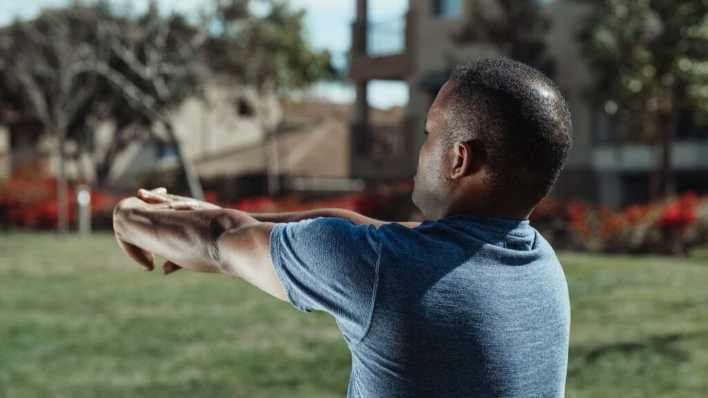 A man stretching his arms in a park, embracing a healthy lifestyle