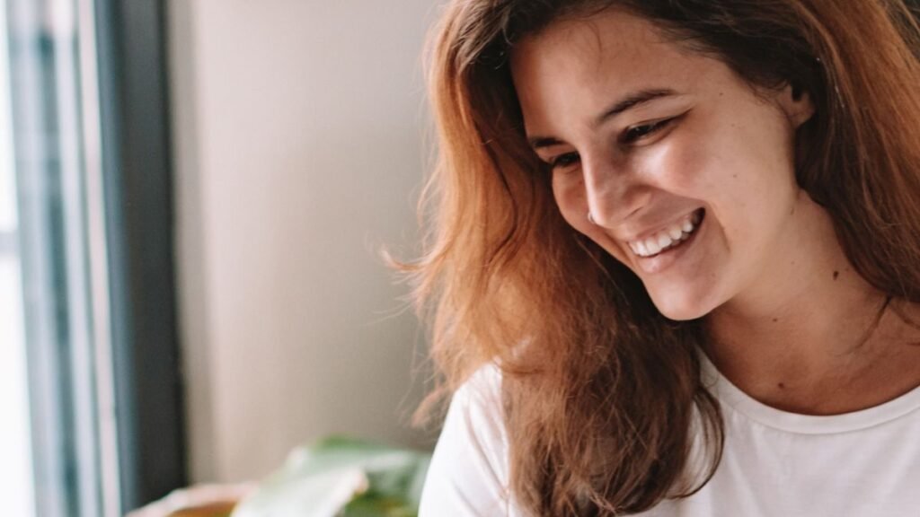 Smiling woman pointing warmly at her laptop screen while working