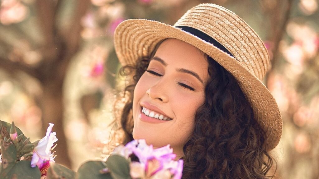 Smiling woman with eyes closed, embracing vibrant spring flowers outdoors