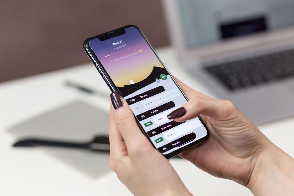 Person holding a smartphone at a desk, representing digital distractions at work