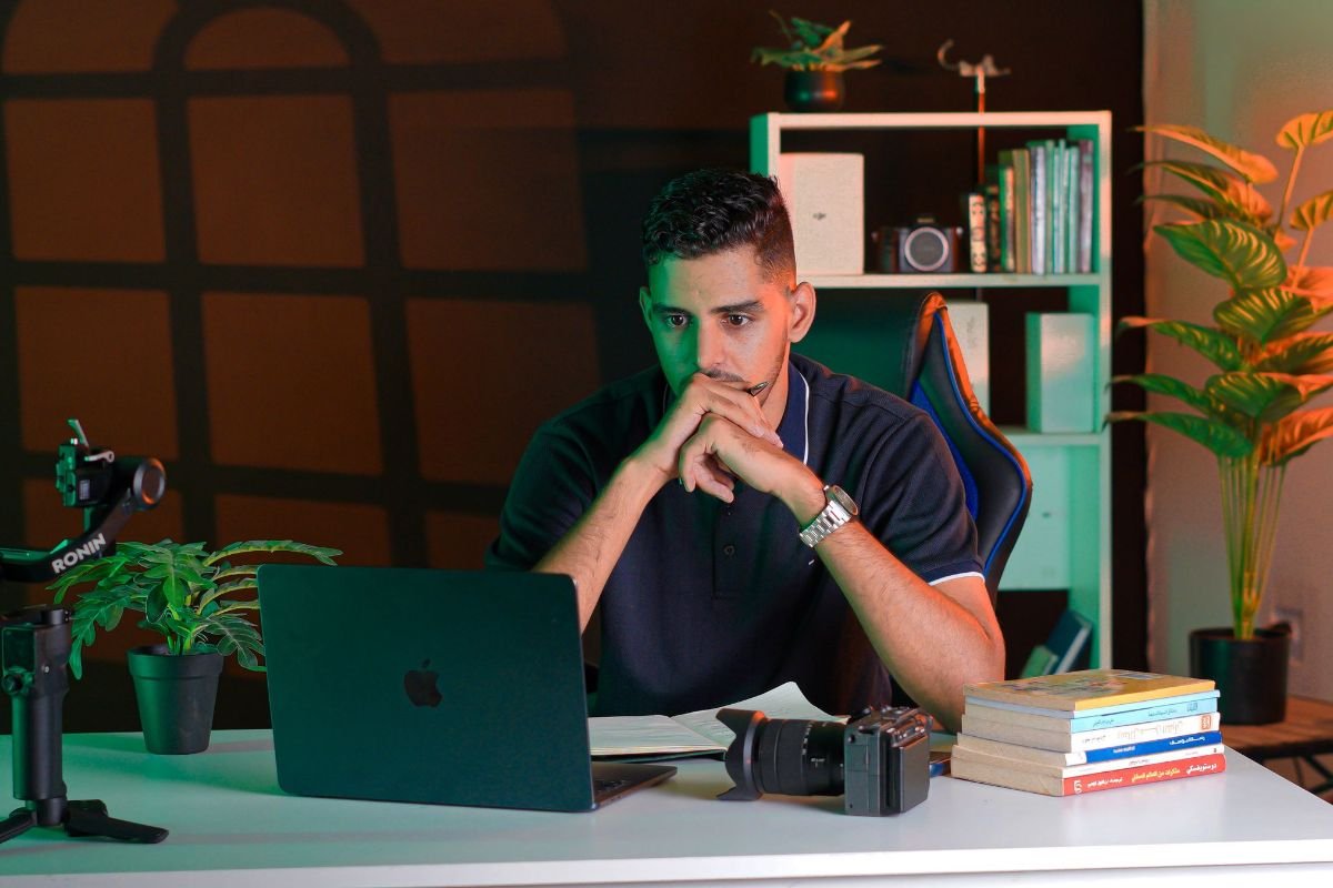 Focused person working at a desk with a laptop and books