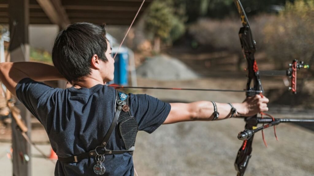 Man aiming a bow and arrow outdoors, showcasing focus