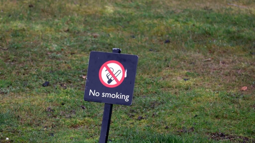 No smoking sign on a green lawn indicating a smoke-free outdoor area