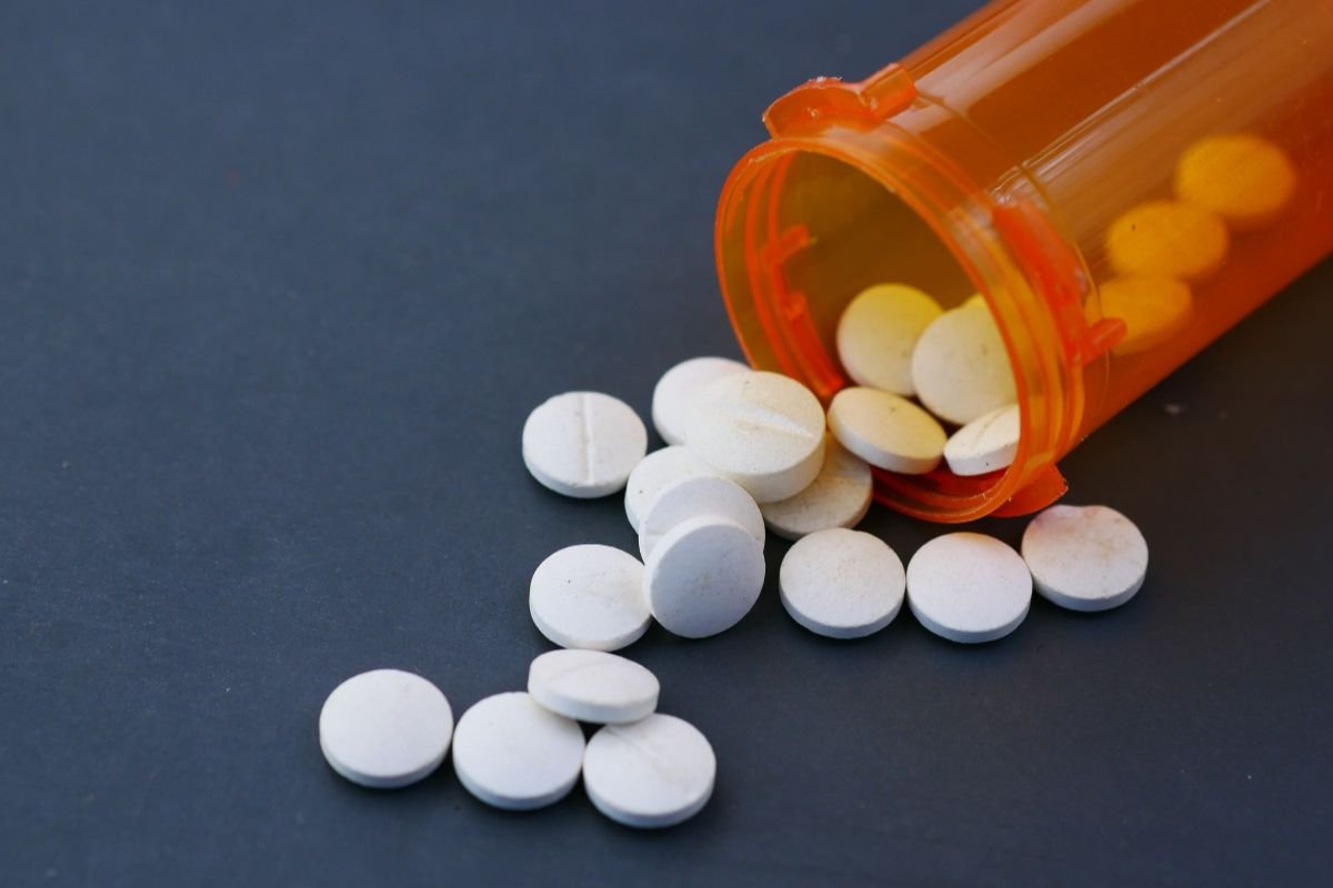White pills scattered from a prescription bottle, representing medication options