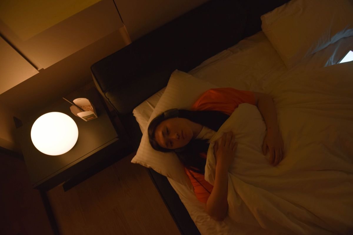 Woman lying awake in bed at night under dim lighting, illustrating the sleep-anxiety connection