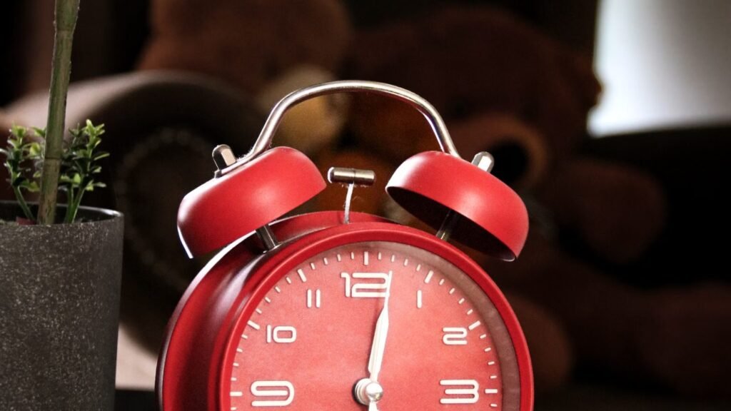 A vibrant red alarm clock on a polished desk