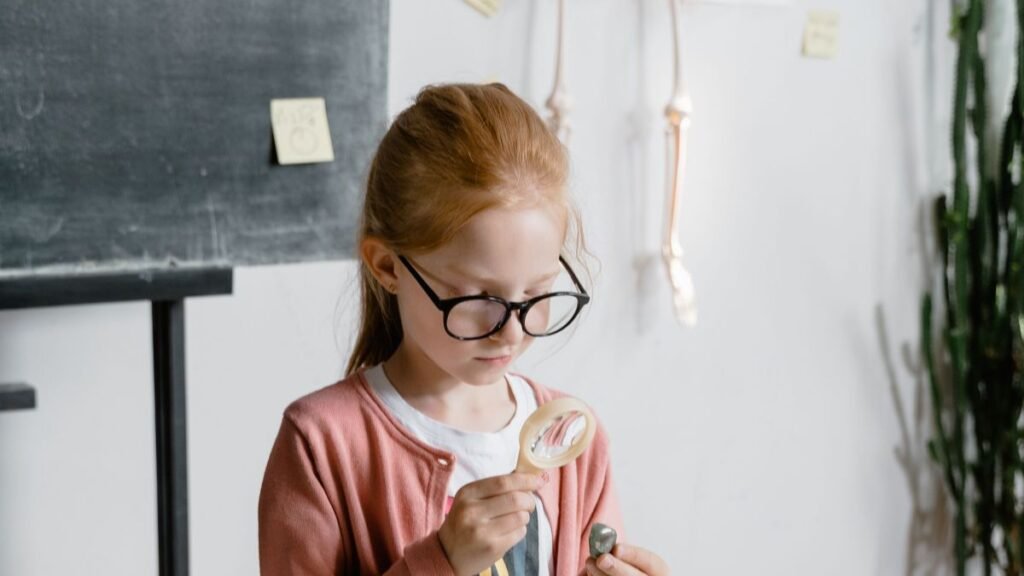 A curious child examines a rock using a magnifying glass