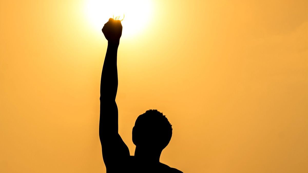 Silhouette embracing self-confidence with arms raised at sunset