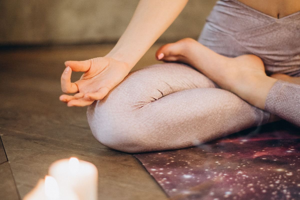 Person meditating with calming candles, combining relaxation practices