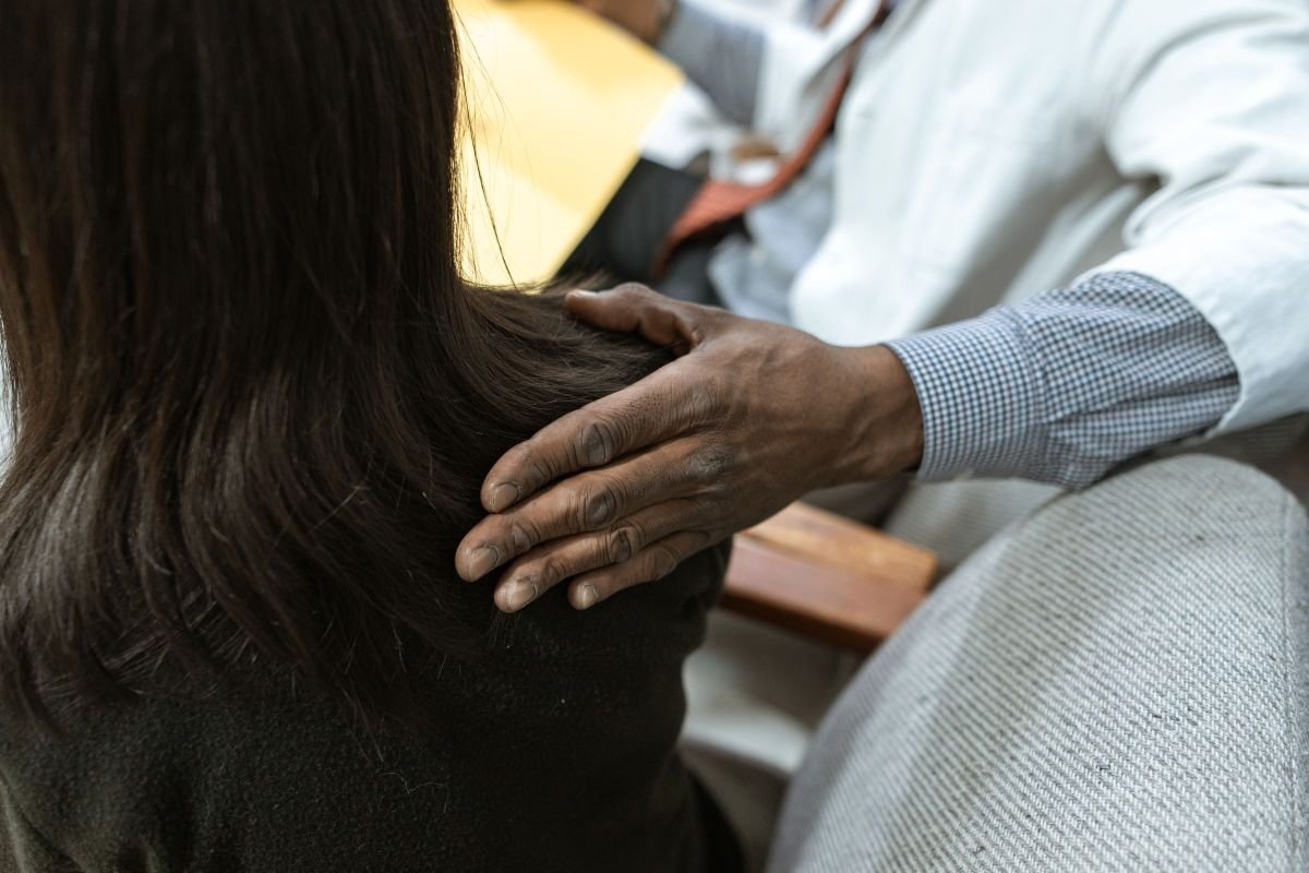Close-up of a supportive hand on a person's shoulder, showing empathy and compassion