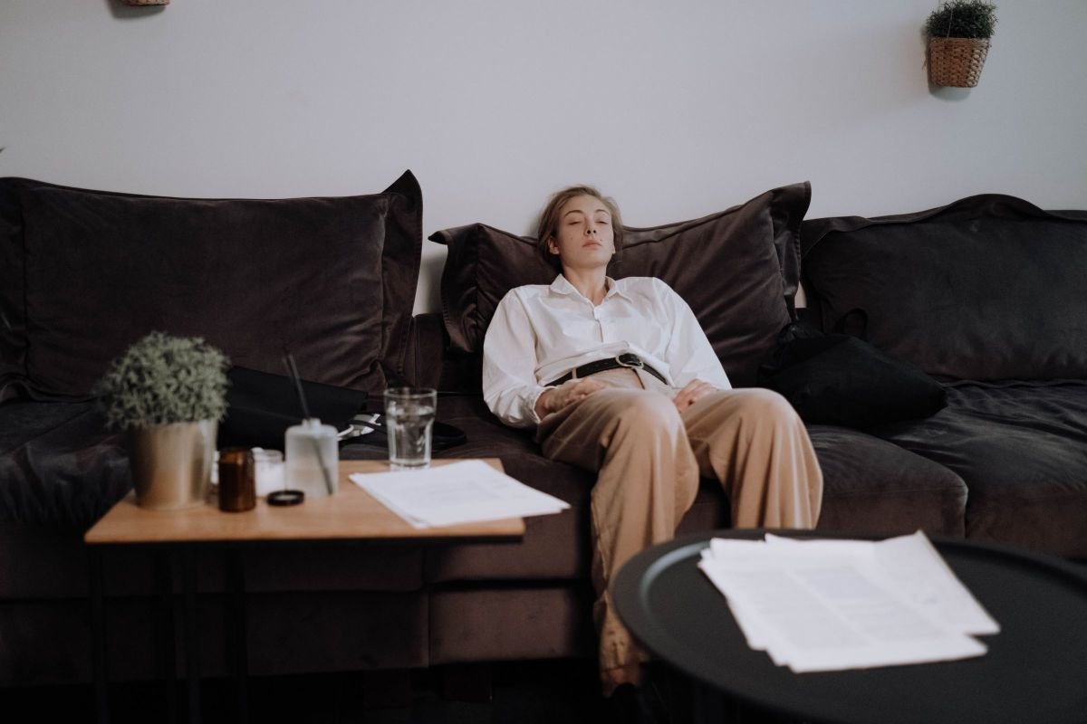Woman sitting relaxed on a couch with eyes closed, representing a hypnotherapy session