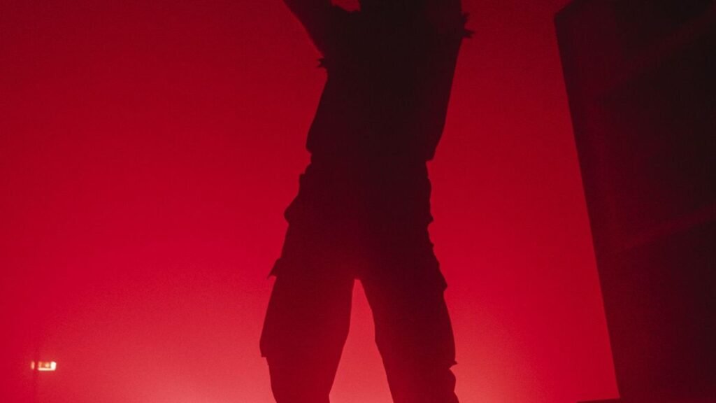 Silhouette of a person standing on stage under a dramatic red spotlight