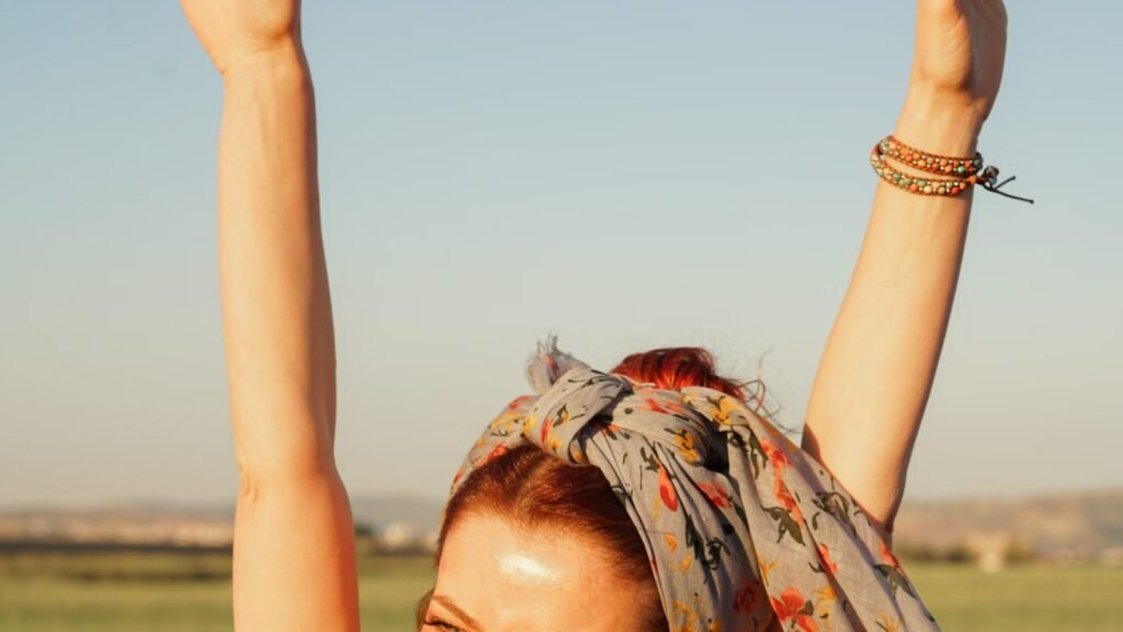 Smiling woman with arms raised joyfully in a sunlit field