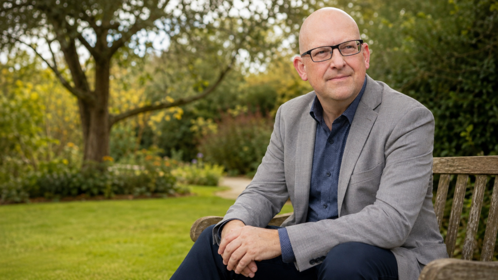 Mark Darlington seated outdoors in a garden, listening calmly
